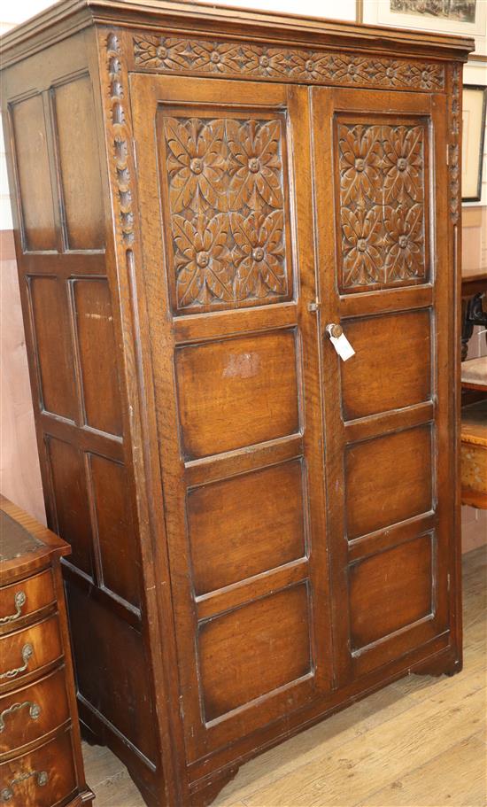 A 1920s carved oak two door wardrobe W.111cm